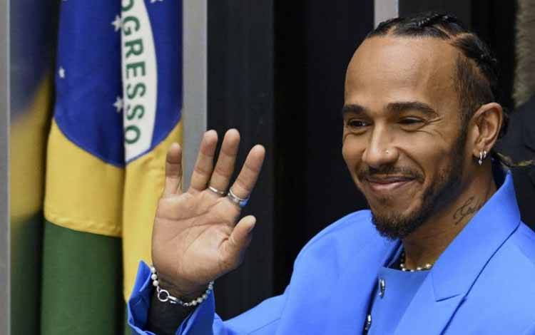 Pebalap Formula 1 Lewis Hamilton melambaikan tangan saat menerima gelar warga negara kehormatan Brasil pada upacara di Kongres Nasional Brasil, di Brasilia. (7/11/2022) (AFP/EVARISTO SA)