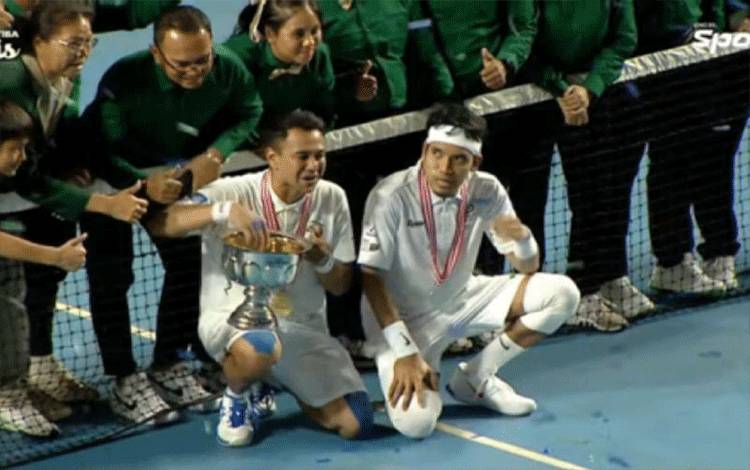 Hasil tangkap layar Raffi Ahmad (kiri bawah) memegang trofi usai mengalahkan Deddy Mahendra Desta (kanan bawah) berfoto bersama hakim garis dan bellboy pada pertandingan olahraga Tiba-Tiba Tenis di Tennis Indoor, Jakarta, Minggu (12/11/2022). (ANTARA/youtube.com/Vindes)