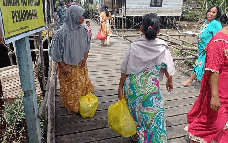 Ibu-ibu di Kelurahan Danau Tundai, Kecamatan Sabangau pulang dengan senyuman setelah mendapatkan sembako murah. (FOTO: HENDRI)