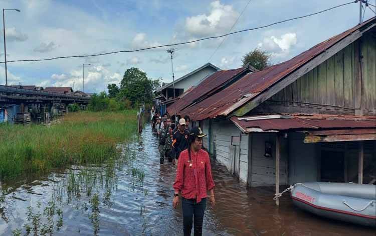  Lurah Langkai, Sri Wanti memantau kondisi banjir dan membagikan bantuan di flamboyan bawah. (FOTO: HENDRI)
