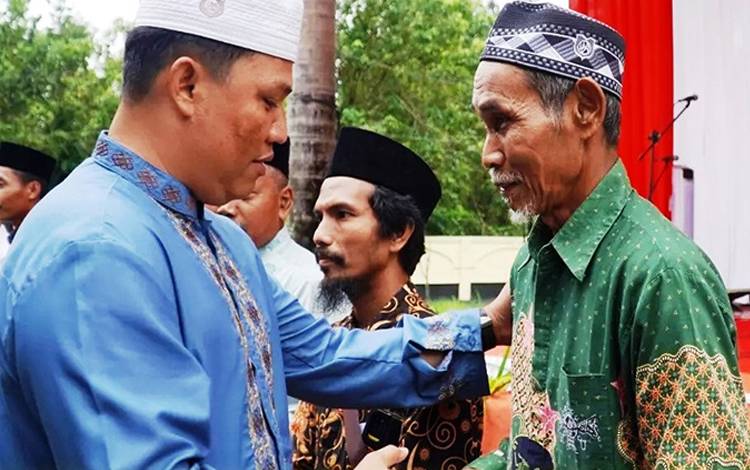 Bupati Hendra Lesmana menyerahkan insentif kepada salah satu guru ngaji di Kabupaten Lamandau. (FOTO : HENDI NURFALAH)