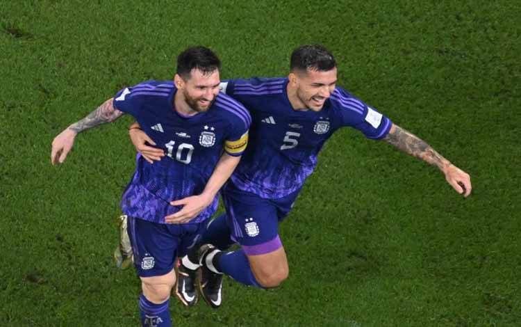 Penyerang dan gelandang Argentina Lionel Messi (kiri) dan Leandro Paredes merayakan kemenangan mereka atas Polandia seusai pertandingan terakhir Grup C Piala Dunia 2022 di Stadium 974, Doha, Rabu (30/11/2022). Argentina menang 2-0 atas Polandia. (AFP/ANTONIN THUILLIER)