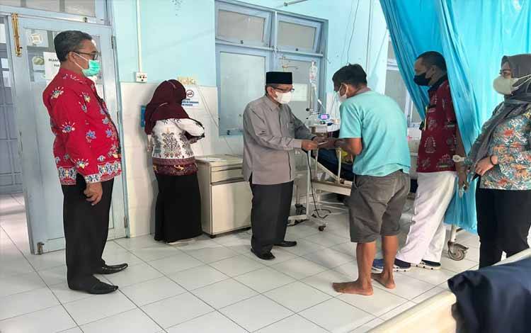 Ketua Baznas Kapuas, KH Nurani Sarji saat menyerahkan bantuan kepada pasien yang tengah dirawat di RSUD dr H Soemarno Sosroatmodjo pada Jumat, 9 Desember 2022. (FOTO: IST)