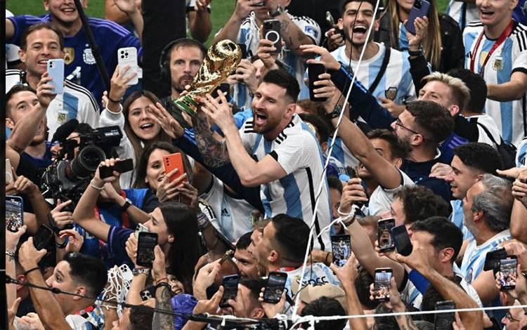 Kapten timnas Argentina Lionel Messi menggenggam trofi Piala Dunia dalam selebrasi bersama rekan-rekan satu tim setelah final Piala Dunia Qatar 2022 antara Argentina dan Prancis di Stadion Lusail, Qatar, 18 Desember 2022. (Photo by Jewel SAMAD / AFP) (AFP/JEWEL SAMAD)
