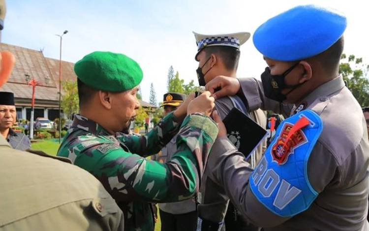 Dandim 1015 Sampit Letkol Inf Abdul Hamid memasangkan pita terhadap anggota Polri, saat apel gelar pasukan Operasi Lilin Telabang 2022. (FOTO: HAMIM)
