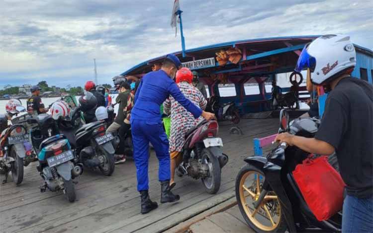 Personel Satpolairud Polres Kapuas saat membantu pengaturan penumpang di feri penyeberangan Jalan Mawar, Sabtu, 24 Desember 2022. (FOTO: IST)