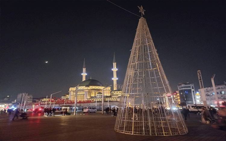 Ornamen berbentuk pohon natal raksasa dengan latar belakang mesjid Taksim di Taksim Meydan, Istanbul.