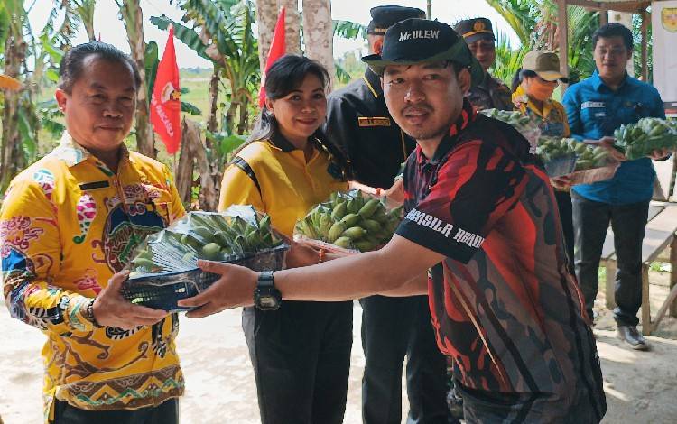 Sekretaris Sapma PP Gunung Mas Mitra Tanjung saat memberikan hasil bumi dari petani setempat kepada Kepala Dinas Pertanian Gunung Mas Letus Guntur, Kamis, 29 Desember 2022. (FOTO: RISKA YULYANA)