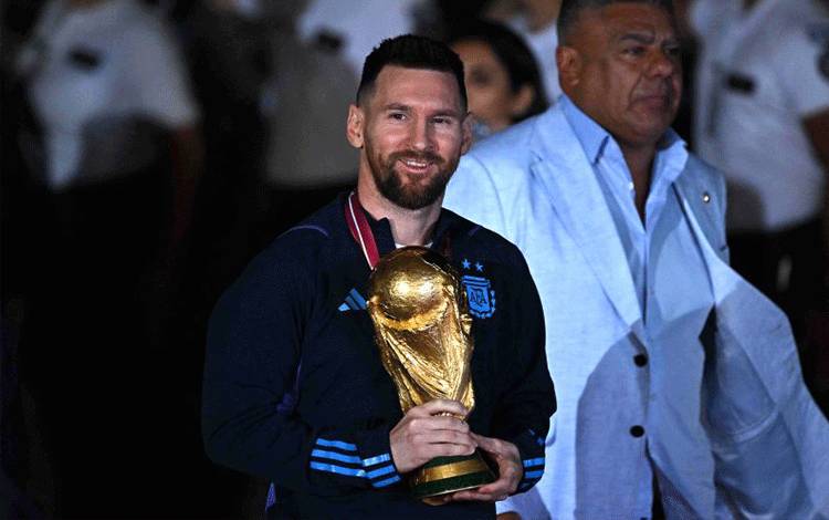 Lionel Messi memegang Tropi Piala Dunia FIFA saat tiba di Bandara Ezeiza International, Buenos Aires, Argentina pada 20 Desember 2022. ANTARA/AFP/LUIS ROBAYO.