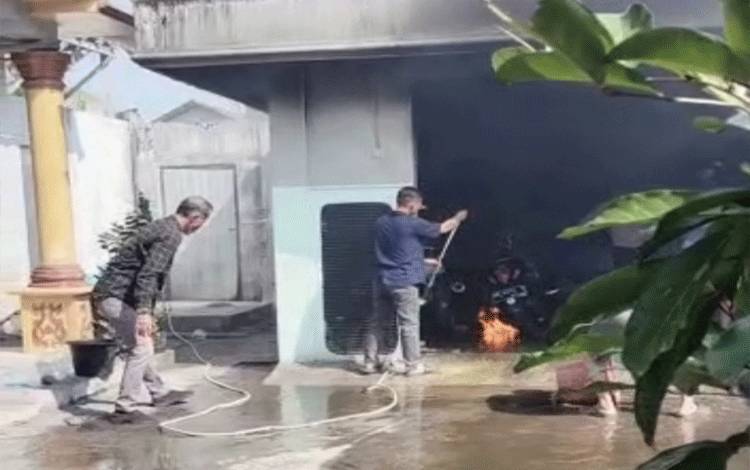 Warga berusaha memadamkan api yang membakar motor metic jenis scopy dengan peralatan seadanya.(FOTO : AGUS FATARONI M)