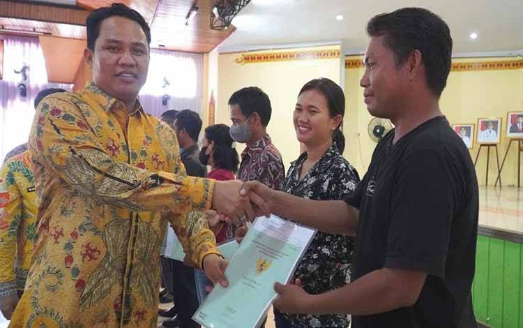 Bupati Lamandau Hendra Lesmana menyerahkan sertifikat program PTSL kepada salah satu penerima hak. (FOTO : HENDI NURFALAH)