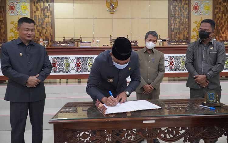 Setelah disahkan pihak legislatif, Bupati Lamandau Hendra Lesmana menandatangani dokumen Ranperda. (FOTO : HENDI NURFALAH)