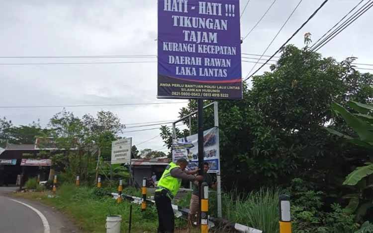 Personel Satlantas Polres Kapuas saat menunjukkan spanduk imbauan yang baru dipasang di Jalan lintas Trans Kalimantan, Kecamatan Basarang pada Jumat, 20 Januari 2023. (FOTO: IST)
