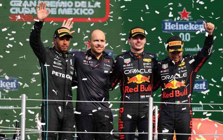 Pebalap tim Red Bull Racing Max Verstappen (kedua kanan) dan Sergio Perez (kanan) dan pebalap Mercedes Lewis Hamilton (kiri) melambaikan tangan di podium balapan Formula 1 di Meksiko, Minggu waktu setempat (30/10/2022). HO/Formula1-Red Bull Racing