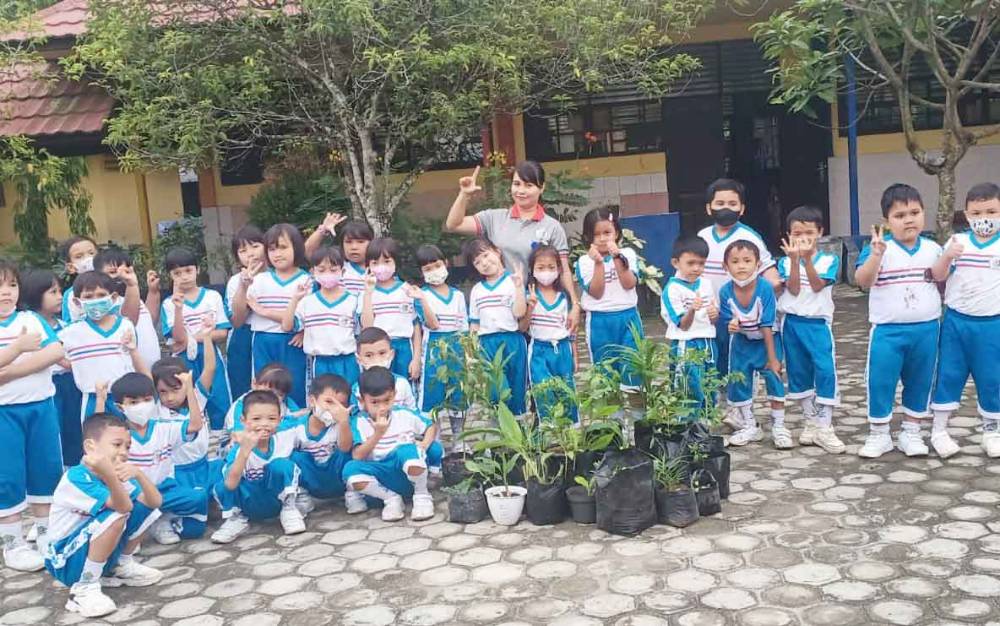 Anak-anak peserta didik sekolah dasar berfoto bersama wali kelasnya usai melakukan aksi penanaman sayur dan tanaman obat di lingkungan sekolah.(FOTO: TESTI PRISCILLA)