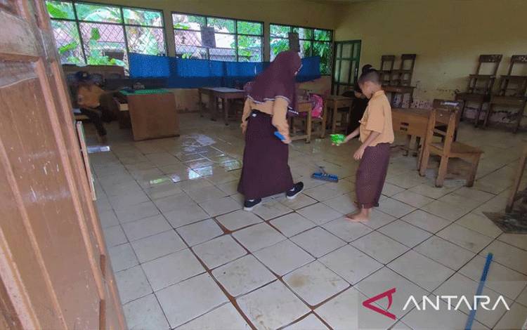 Siswa sekolah membersihkan ruang kelas yang tergenang semasa banjir di bagian wilayah Kabupaten Tapin, Provinsi Kalimantan Selatan, Sabtu (4/2/2023). (ANTARA/Muhammad Fauzi Fadilah)