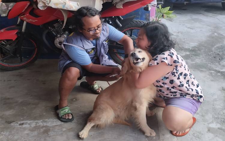 Vaksinator Rabies memberikan vaksin rabies kepada hewan peliharaan milik warga Kota Palangka Raya.(FOTO: TESTI PRISCILLA)