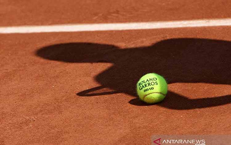 ilustrasi - Bola resmi turnamen tenis dengan bayang-bayang seorang pemain tenis diatas tanah. ANTARA/Shutterstock/pri.