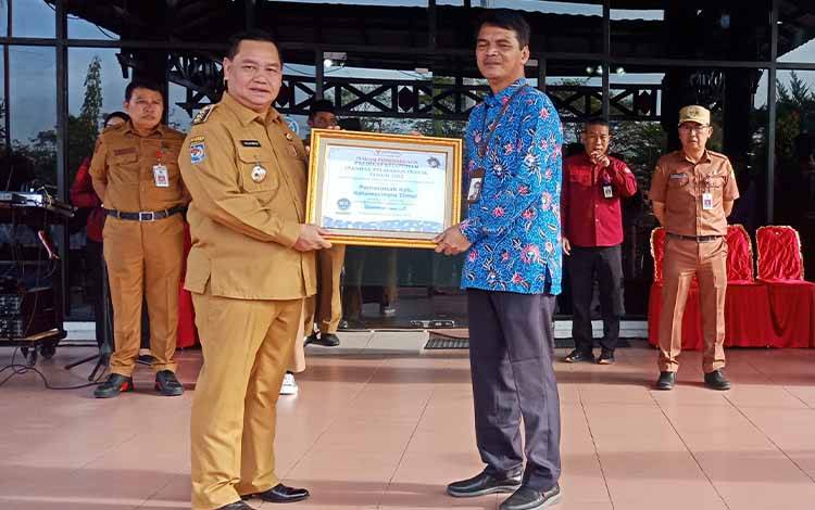 Bupati Kotawaringin Timur, Halikinnor menerima penghargaan Ombudsman pelayanan publik terbaik dari Kepala Perwakilan Ombudsman Kalteng Raden Biroum, Senin,  20 Februari 2023. (FOTO: DEWIP) 