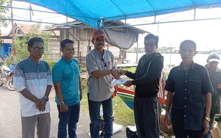 Anggota DPRD Kapuas, Thosibae Limin saat menyalurkan bantuan kepada kelompok nelayan di Kelurahan Selat Hulu, Selasa, 21 Februari 2023. (FOTO: IST)