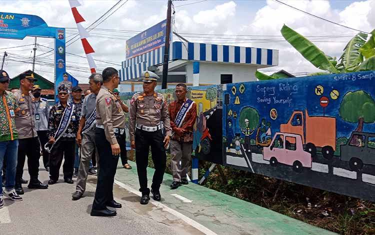 Kasi Dikpen Subbiddikmas Ditkamsel Korlantas Polri AKBP Arief Bahtiar mengamati salah satu grafiti karya SMPN 8 Sampit di Kampung tertib lalu lintas, Kelurahan Baamang Barat, Kamis, 23 Februari 2023. (FOTO: DEWIP)