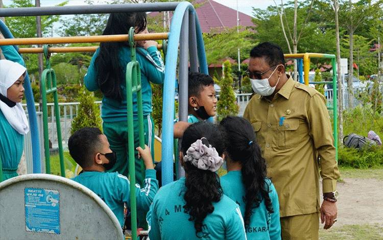 Kepala DPPKBP3APM Palangka Raya, Sahdin Hasan mendampingi anak-anak bermain di taman Nyahu Papan Taliwu. (FOTO: HENDRI)