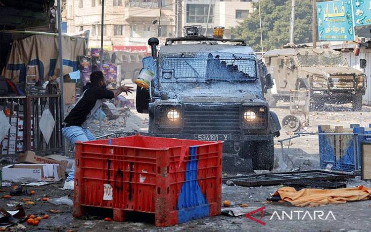 Warga Palestina melemparkan ember cat ke kendaraan tentara Israel saat terjadinya serangan di kawasan Nablus yang telah diduduki tentara Israel, Tepi Barat, Rabu (22/2/2023). ANTARA FOTO/Reuters-Raneen Sawafta/nym.