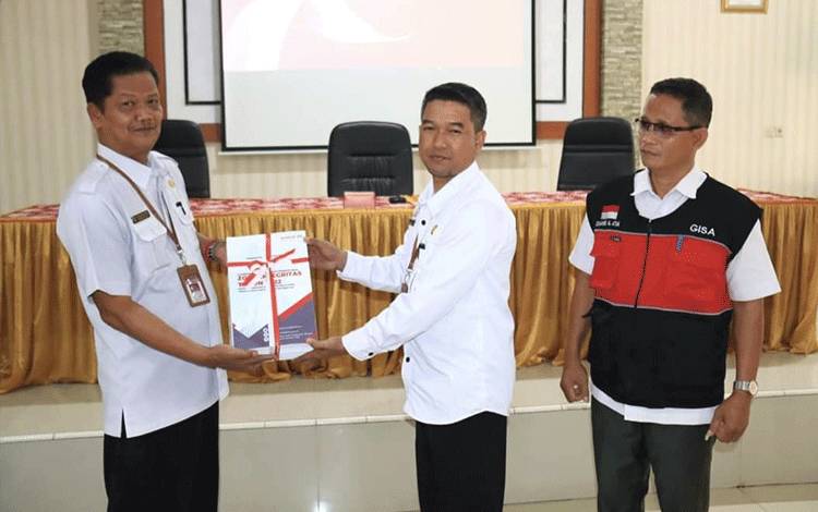 Kepala DPMPTSP Seruyan, Agung Setiawan menyerahkan dokumen pelaksanaan Zona Integritas kepada Sekda Seruyan Djainuddin Noor ( FOTO: PROKOM SERUYAN)