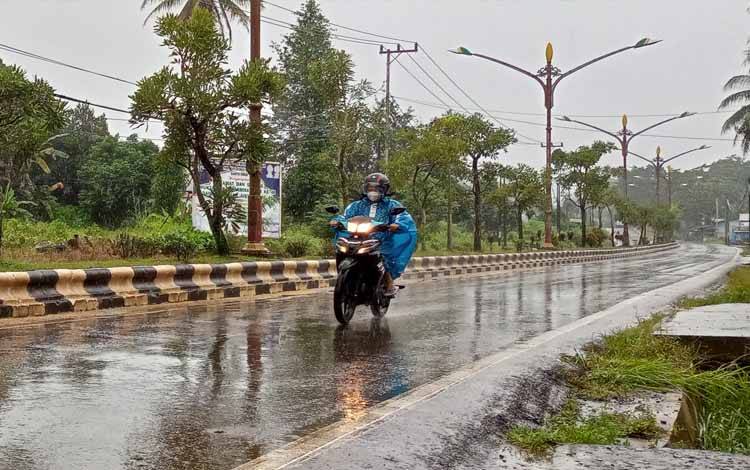 Pengendara sepeda motor mengenakan jas hujan saat hujan dengan intensitas sedang mengguyur Kota Tamiang Layang Kabupaten Barito Timur. (FOTO: BOLE MALO)