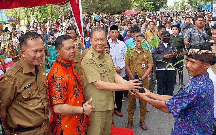 Wakil Ketua I DPRD Kapuas, Yohanes (baju batik) hadiri penyerahan simbolis bibit pohon kepada warga saat pawai budaya, belum lama ini. (FOTO: DODI)
