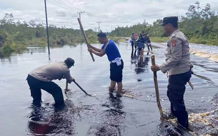 Petugas Polsek Timpah membuat tanda untuk pembatas jalan yang berlubang akibat banjir, Jumat (31/3/2023). (ANTARA/HO-Polsek Timpah)