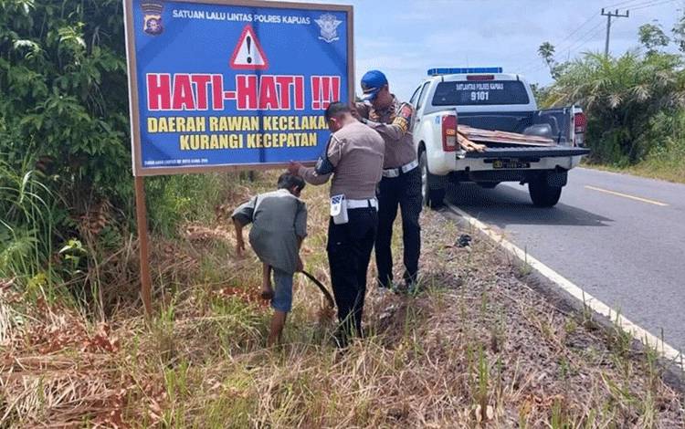 Personel Satlantas Polres Kapuas saat pasang spanduk imbauan di Jalan Trans Kalimantan Palangka Raya - Buntok di wilayah Kecamatan Timpah. (FOTO: IST)