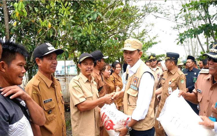 Bupati Barito Utara H Nadalsyah didampingi Sekda Muhlis, unsur FKPD, kepala OPD menyerahkan bantuan beras kepada warga terdampak banjir di wilayah Kecamatan Teweh Selatan. (foto: Dhani)