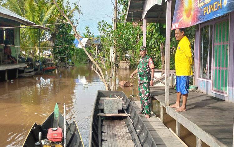 Babinsa Koramil 1016-01/Pahandut, Pelda Slamet Suyanto memantau kondisi banjir di Kelurahan Kameloh Baru. (FOTO: PENDIM/1016)
