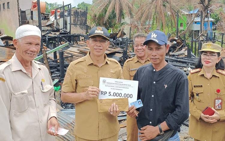Bupati Murung Raya Perdie M. Yoseph saat menyerahkan bantuan uang tunai kepada korban kebakaran di Desa Mangkahui.