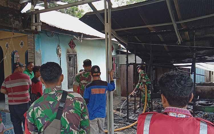 Personel TNI membantu pendinginan puing kios milik Sekojo (57) warga Desa Haringen Kabupaten Barito Timur yang terbakar, Kamis, 13 April 2023. (FOTO: IST)