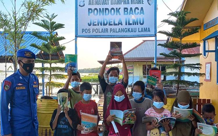 Personel Satpolairud Polres Kapuas saat ajak anak-anak baca buku di perpustakaan pondok baca Pos Polairud, DAS Barito, pada Selasa, 2 Mei 2023. (FOTO: IST)