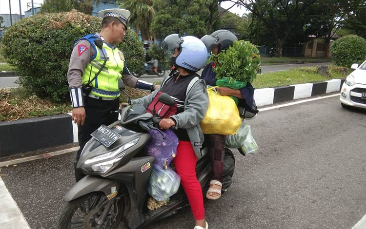 Personel Satlantas Polresta Palangka Raya, pada saat mengedukasi pengendara yang membawa barang berlebihan (FOTO : SATLANTAS POLRESTA PALANGKA RAYA)