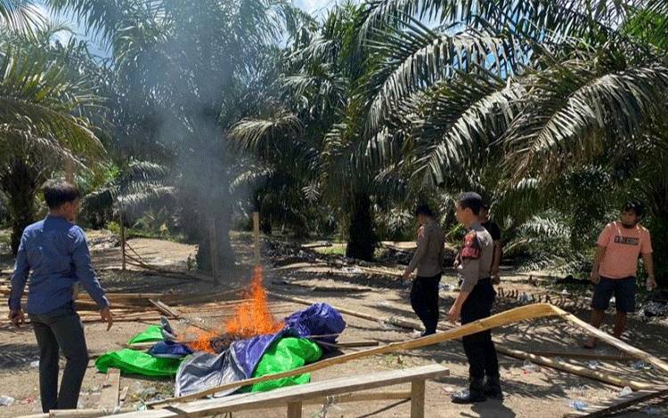 Anggota Polres Lamandau membongkar dan membakar tenda yang diduga dijadikan sarang perjudian. (FOTO : HENDI NURFALAH)