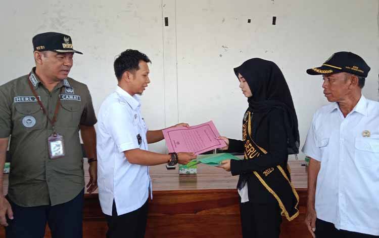 Kades Sungai Undang Ikhwan Arifin saat menyerahkan penghargaan kepada Sonia Larasati yang terpilih sebagai Diang Kabupaten Seruyan. (FOTO: IST)