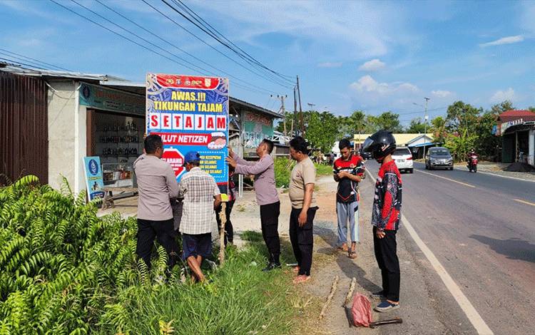 Pemasangan spanduk imbauan cegah laka lantas di Jalan Trans Kalimantan, Kecamatan Kapuas Timur. (FOTO: IST)