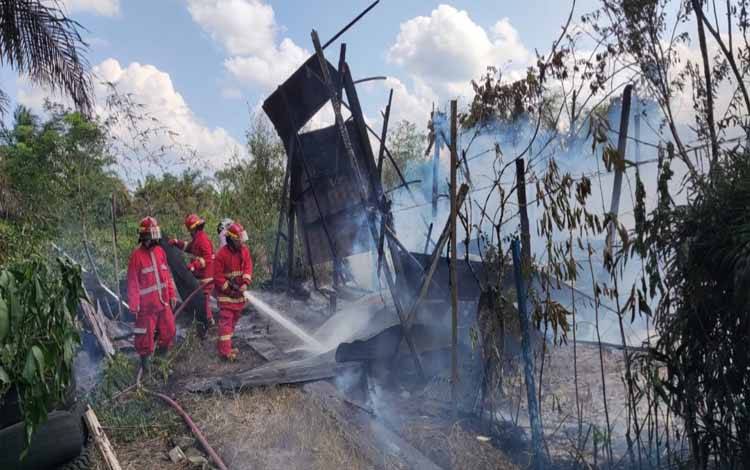 Petugas Damkar Kobaf saat melakukan pendinginan rumah yang ludes terbakar. (FOTO: DANANG)