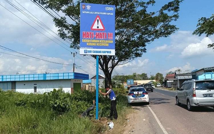 Personel Satlantas Polres Kapuas saat pasang spanduk peringatan rawan laka di Jalan Trans Kalimantan, Minggu, 28 Mei 2023. (FOTO: IST)