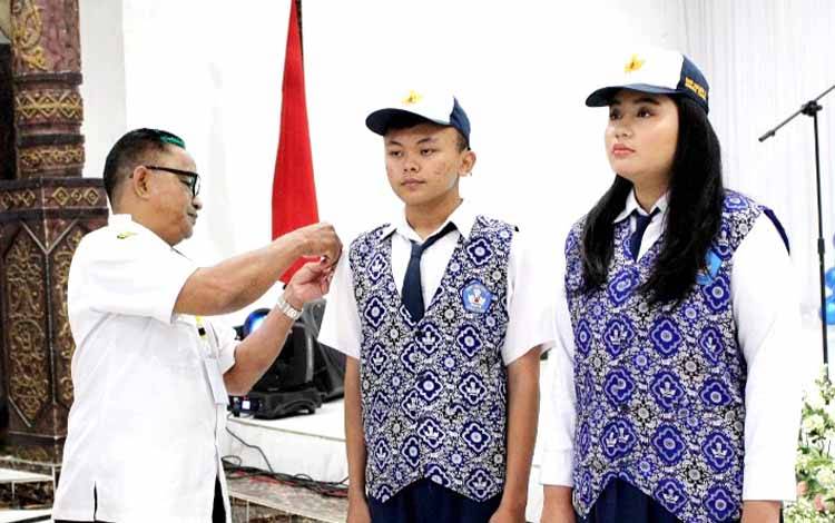 Kepala SMPN 2 Muara Teweh, Hanil melepas atribut perwakilan dua pelajar pada acara pelepasan siswa dan siswi SMPN 2 Muara Teweh, di gedung Balai Antang Muara Teweh. (FOTO: DHANI)