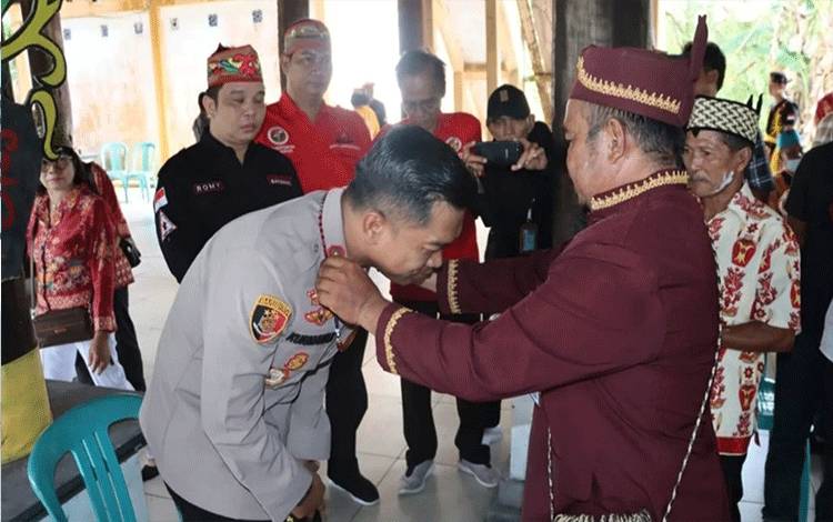 Kapolres Kapuas, AKBP Kurniawan Hartono menerima pemberian cinderamata dari Damang Adat Dadahup, bertempat di Rumah Betang Sei Pasah, Senin, 5 Juni 2023. (FOTO: IST)