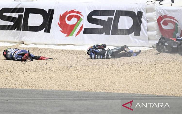 Pebalap Yamaha Fabio Quartararo (kiri) dan pebalap Aprilia Miguel Oliveira terbaring di tanah setelah terlibat kecelakaan di MotoGP Spanyol di Sirkuit Jerez, 30 April 2023. Foto AFP/JORGE GUERRERO