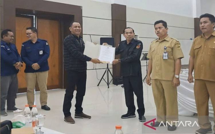 Ketua KPU Gunung Mas Stepenson menyerahkan berita acara pleno kepada Ketua Bawaslu kabupaten Walman Tristianto di Kuala Kurun. (ANTARA/Chandra)