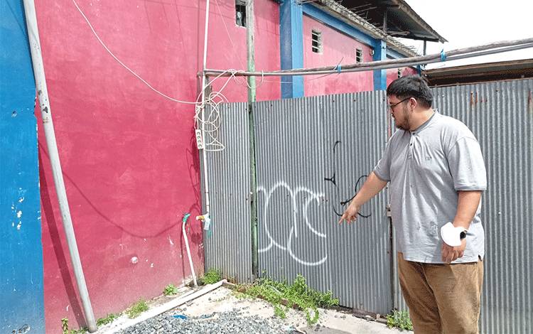 Pemilik toko, Farijd Aziz saat menunjukkan pintu samping tokonya yang di jebol OTK, Jumat, 30 Juni 2023. (Foto : Pathur)