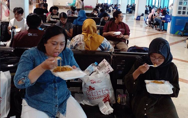 Para penumpang menikmati makanan yang diberikan maskapai Lion Air sebagai kompensasi penundaan keberangkatan, Sabtu, 8 Juli 2023. (FOTO: Istimewa)