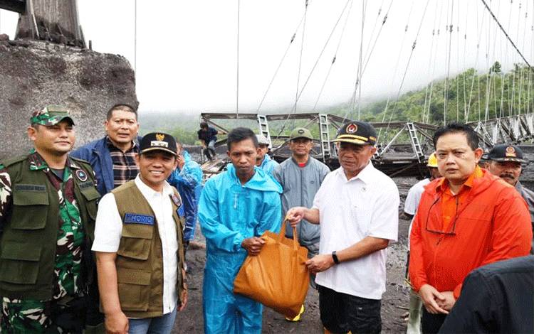 Menko PMK Muhadjir Effendy memberikan bantuan kepada warga yang terisolir di Dusun Bondeli Selatan, Desa Sumberwuluh, Kabupaten Lumajang, Sabtu (8/7/2023). (ANTARA/HO-Diskominfo Lumajang)